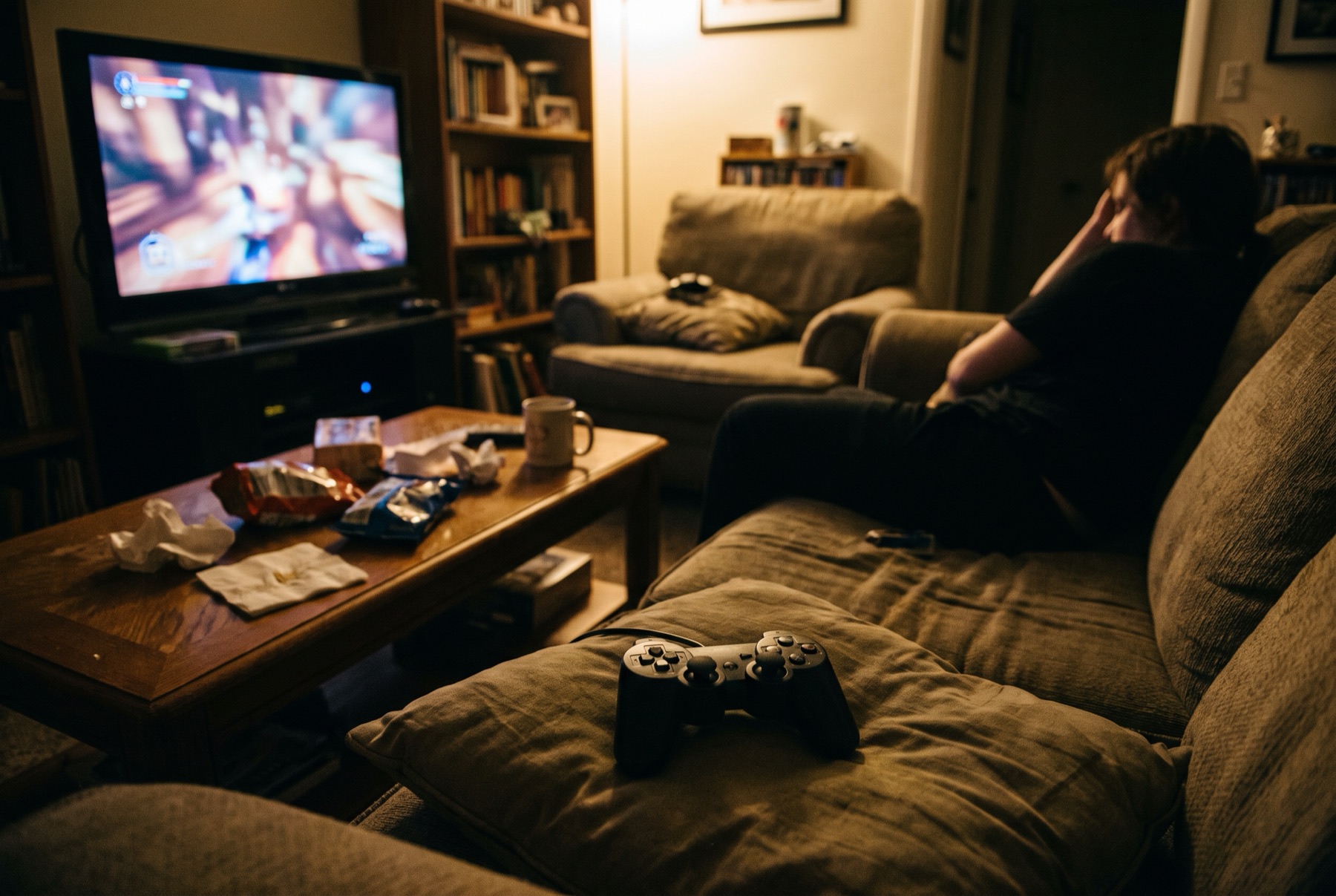 A living room at night lit by a television showing an out-of-focus video game